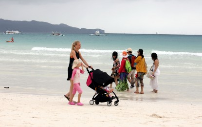 <p>Foreign tourists enjoy a leisurely walk along the beach of Boracay. <em>(PNA file photo)</em></p>
